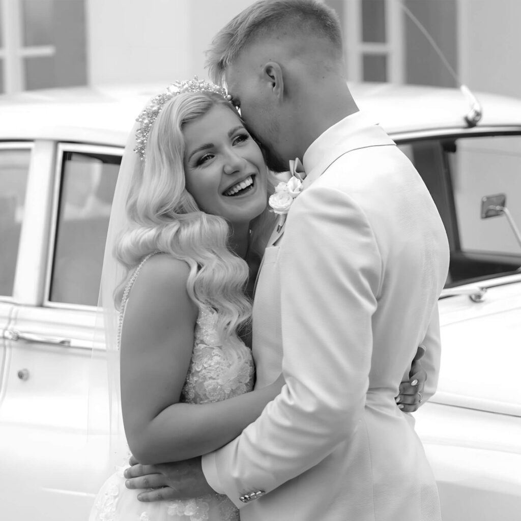 Hochzeitspaar vor einem Oldtimer.